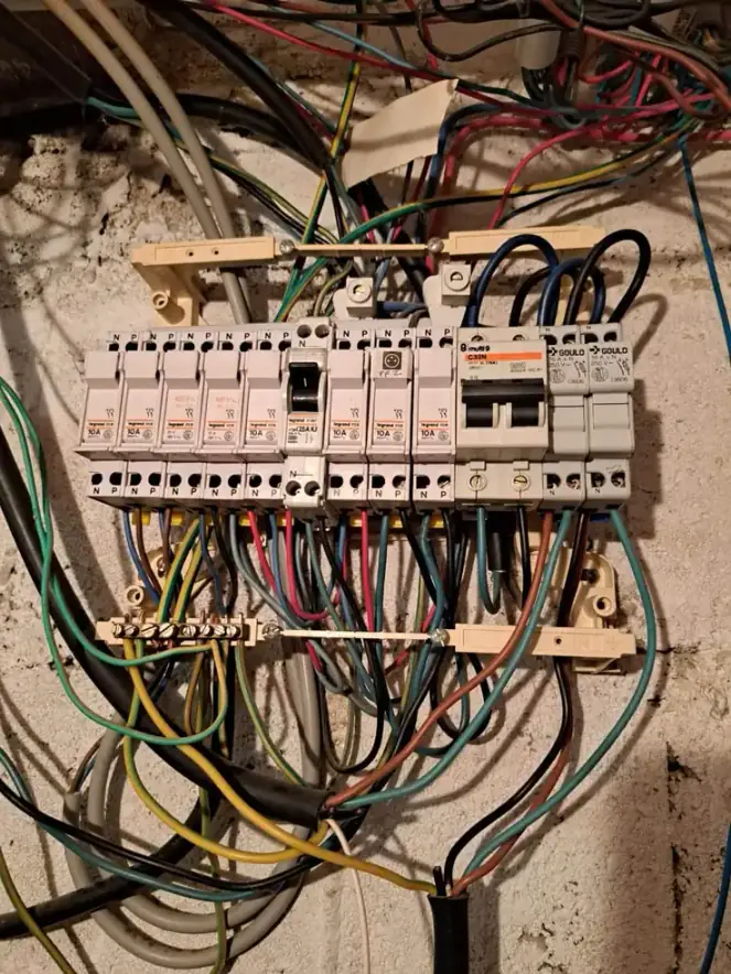 Ancien tableau électrique avec câbles enchevêtrés, avant sa rénovation
