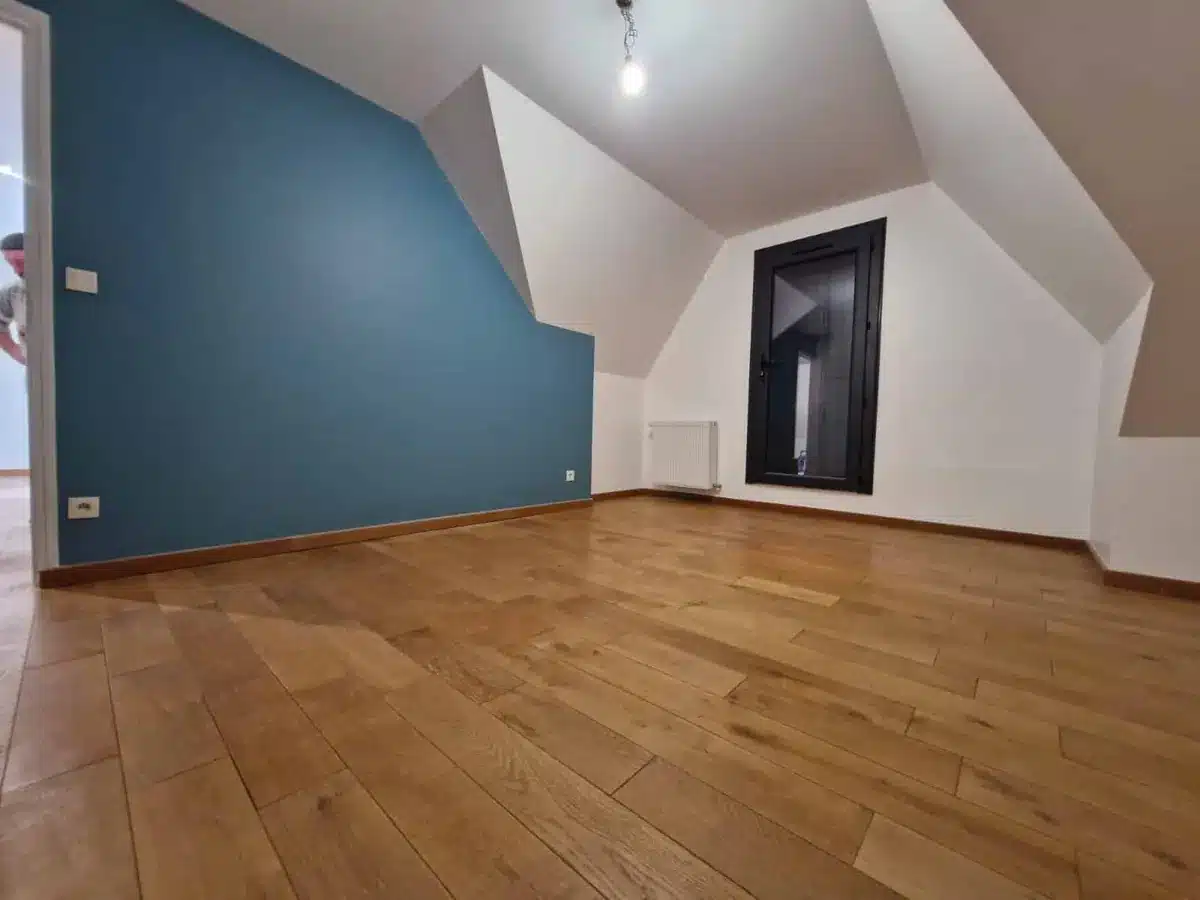 Chambre sous combles avec mur bleu canard, murs blancs et parquet bois