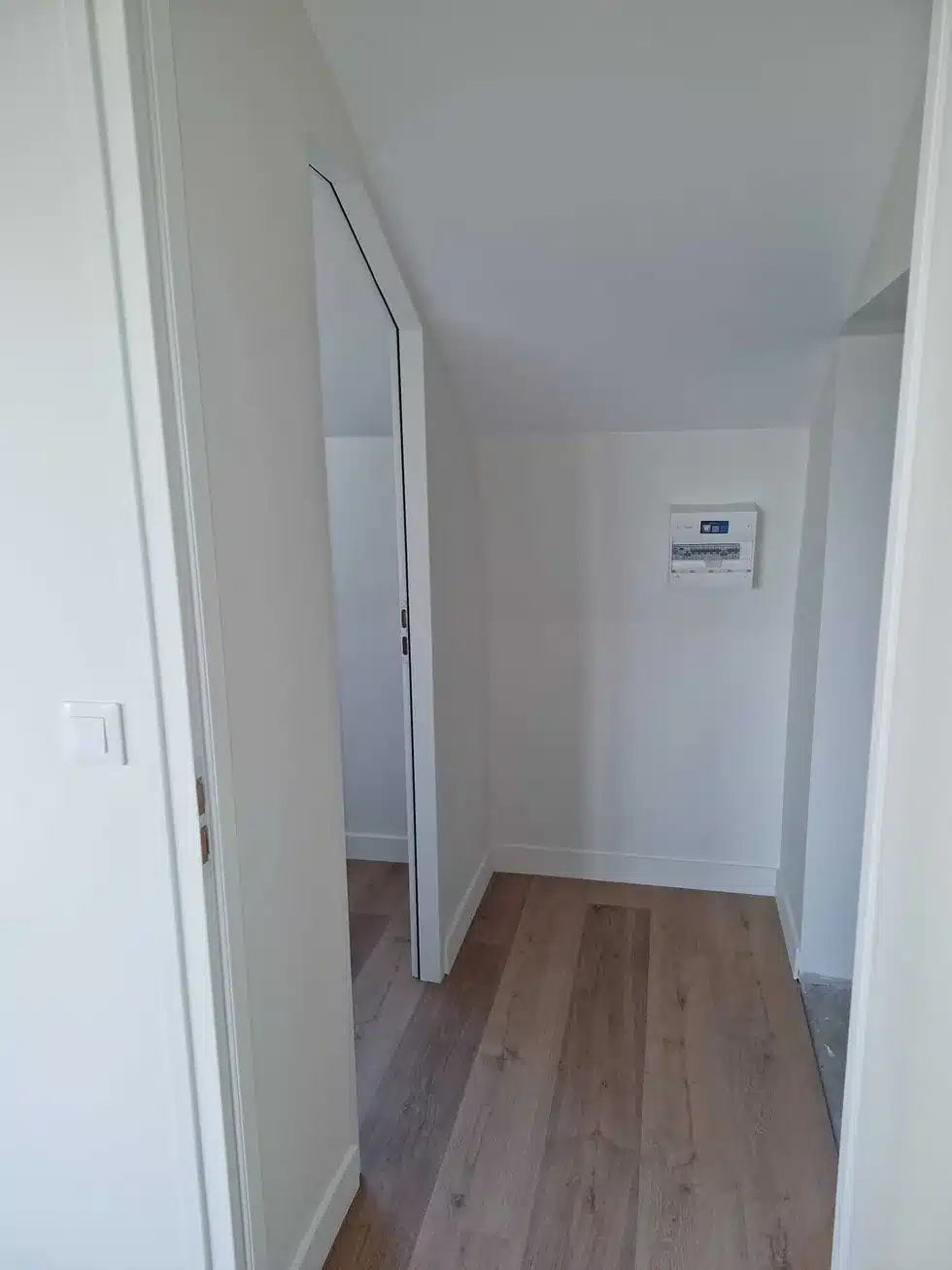 Couloir créé dans des combles aménagés, murs blancs, portes et parquet