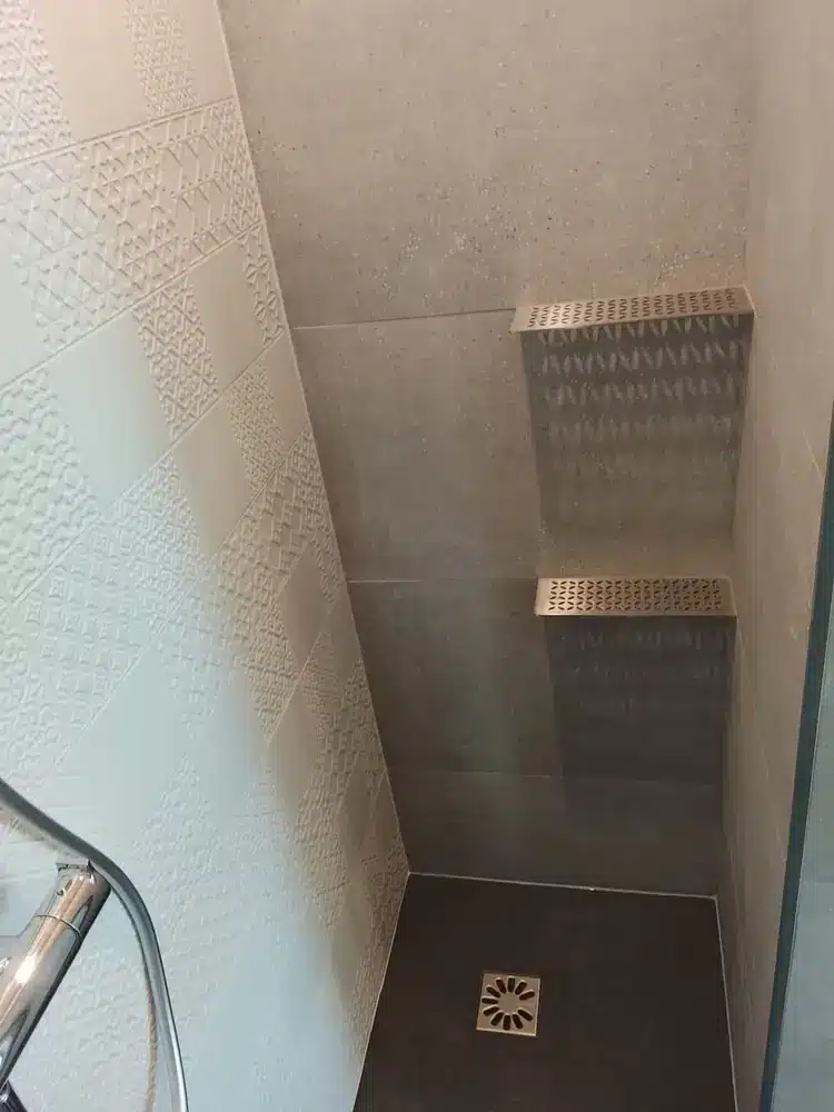 Douche de plain-pied avec receveur sombre, niche murale et faïence en grand format