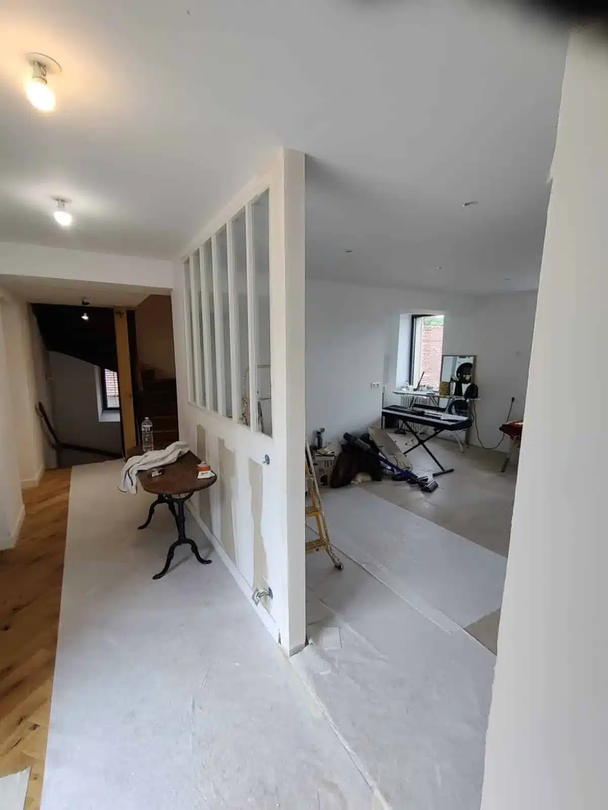 Pièce en travaux avec sol protégé et verrière, pendant la mise en peinture