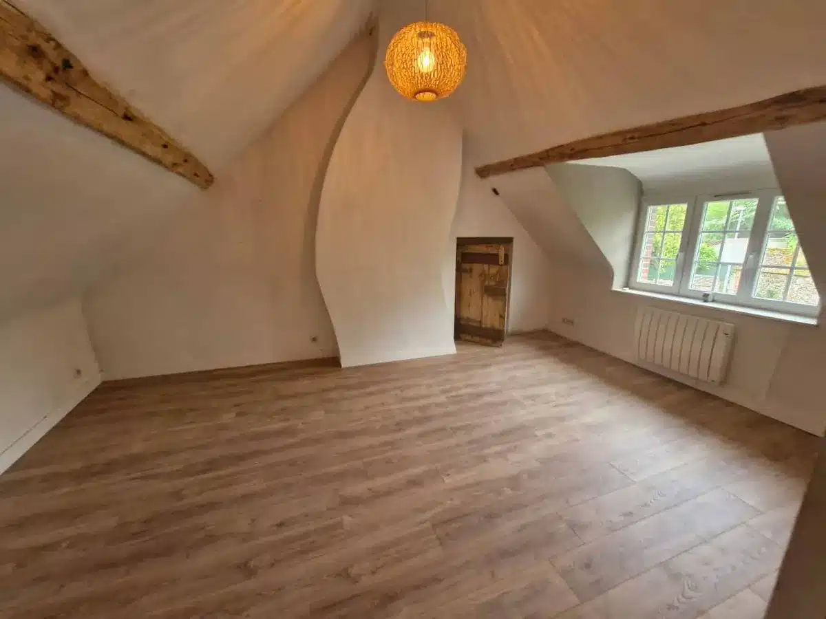 Pièce sous combles avec poutres apparentes, parquet bois et suspension orange