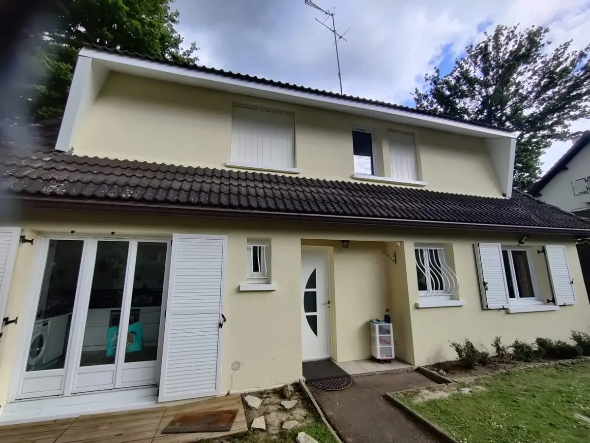 Façade de maison ravalée avec menuiseries blanches et porte d'entrée