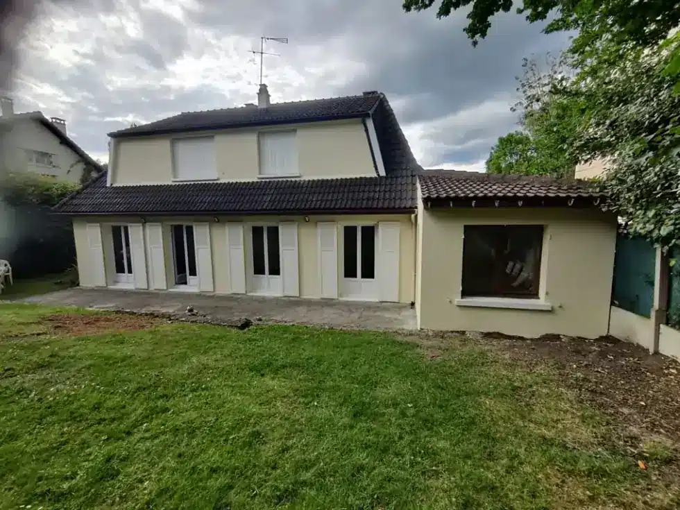 Maison avec façade ravalée de couleur crème, volets et fenêtres repeints, jardin au premier plan