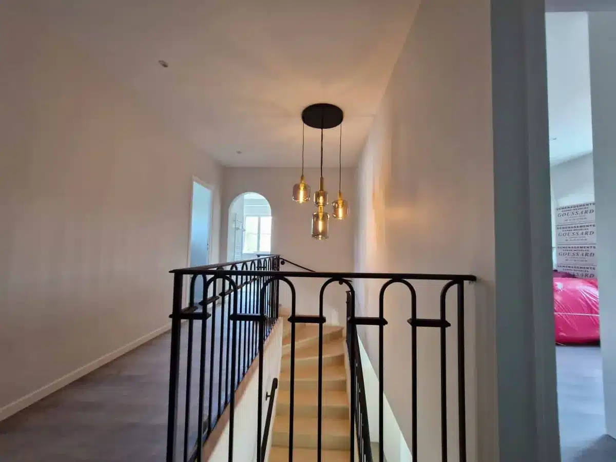 Palier rénové avec garde-corps en fer forgé, suspension design et parquet