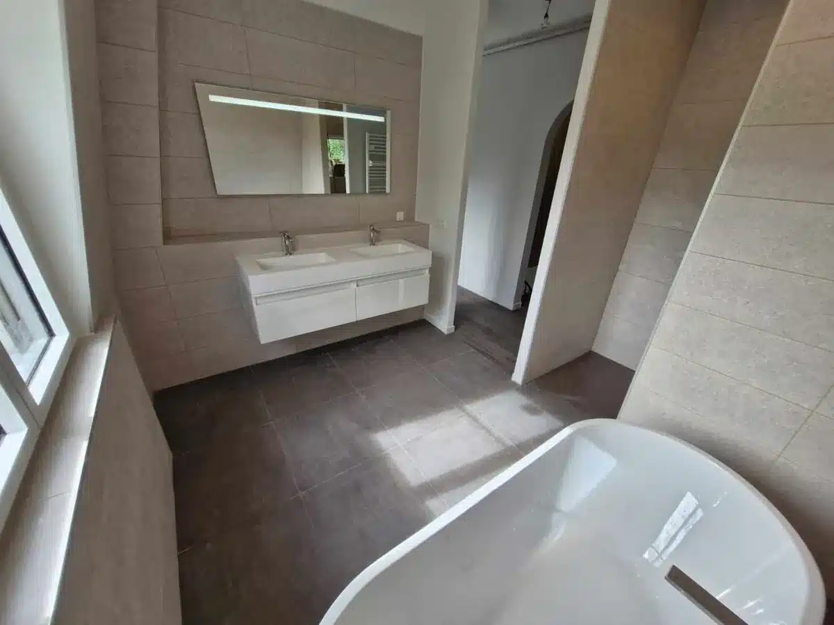Salle de bain avec baignoire, meuble double vasque blanc et grand miroir
