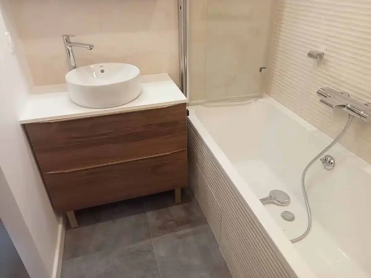 Baignoire habillée de faïence, meuble en bois et vasque blanche à poser