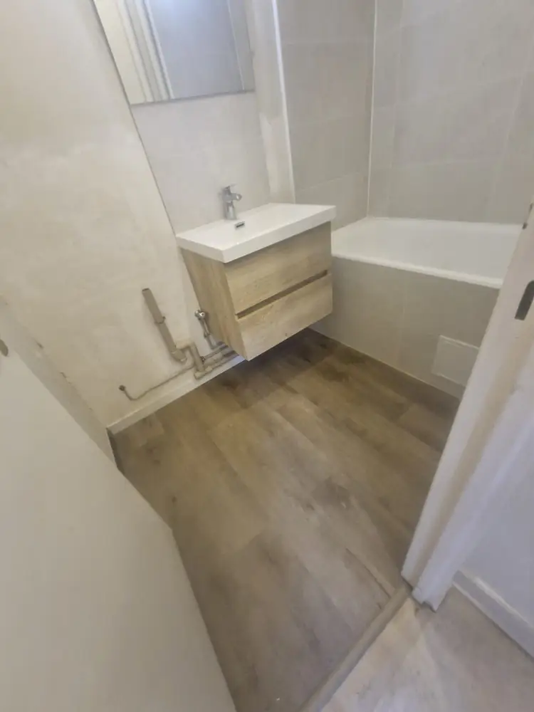 Salle de bains rénovée à Rambouillet avec baignoire, meuble vasque en bois, faïence claire et sol imitation bois